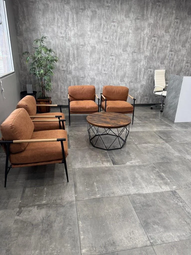 Waiting area at Hair System Salons with brown chairs and a round coffee table